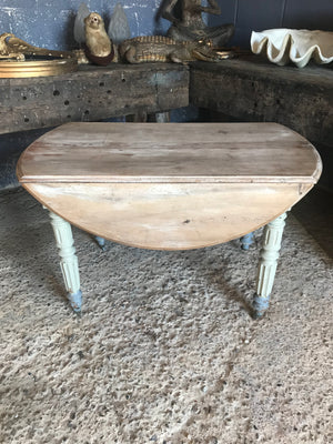 A drop leaf circular bleached pine painted table on castors