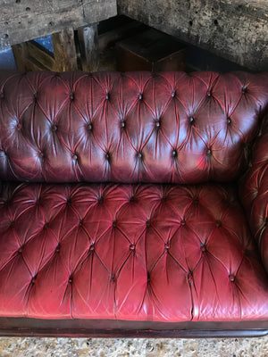 An oxblood two seater Chesterfield sofa with button back and seat