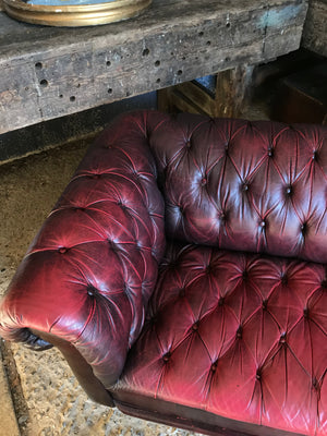 An oxblood two seater Chesterfield sofa with button back and seat