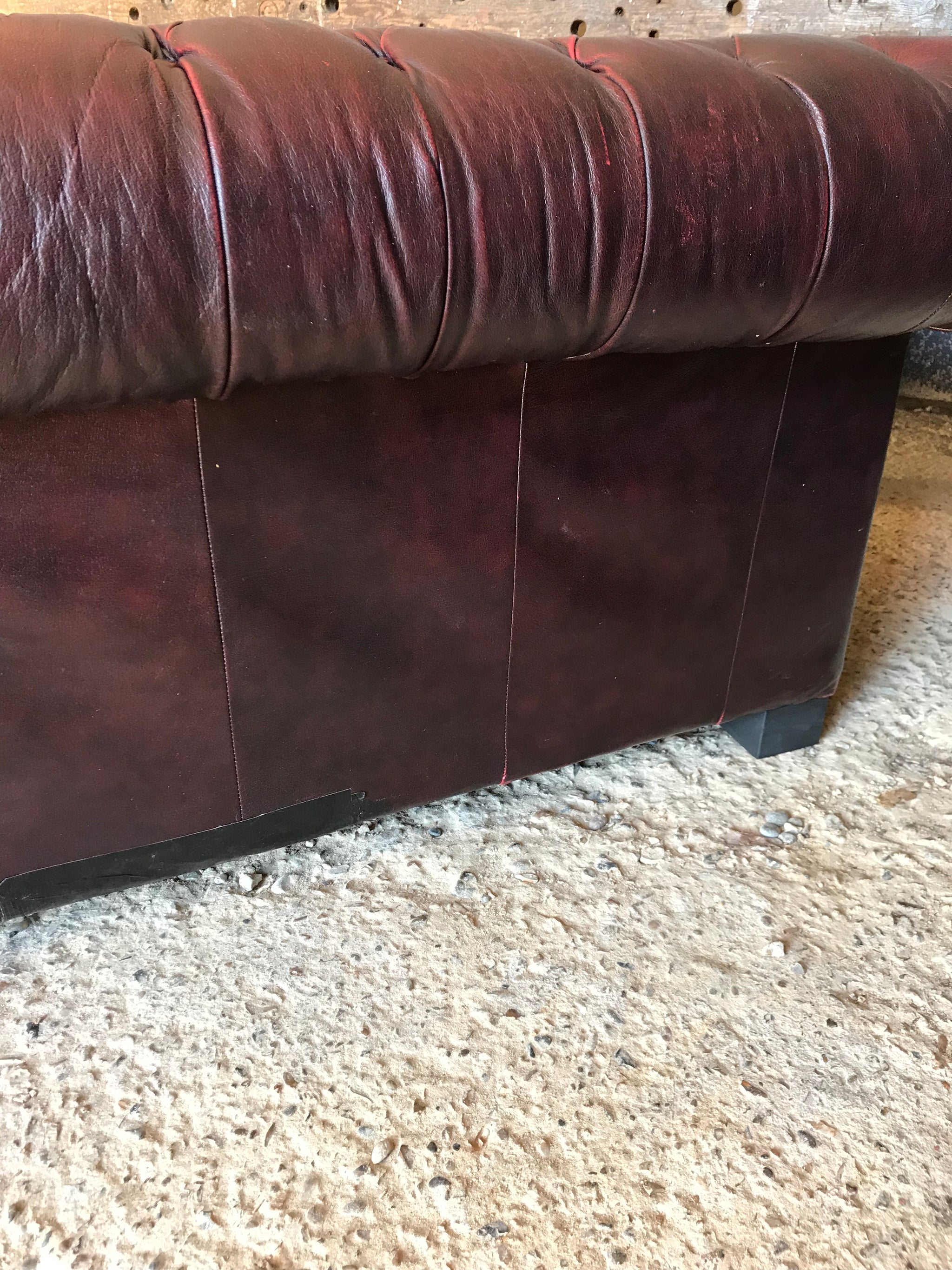 An oxblood two seater Chesterfield sofa with button back and seat
