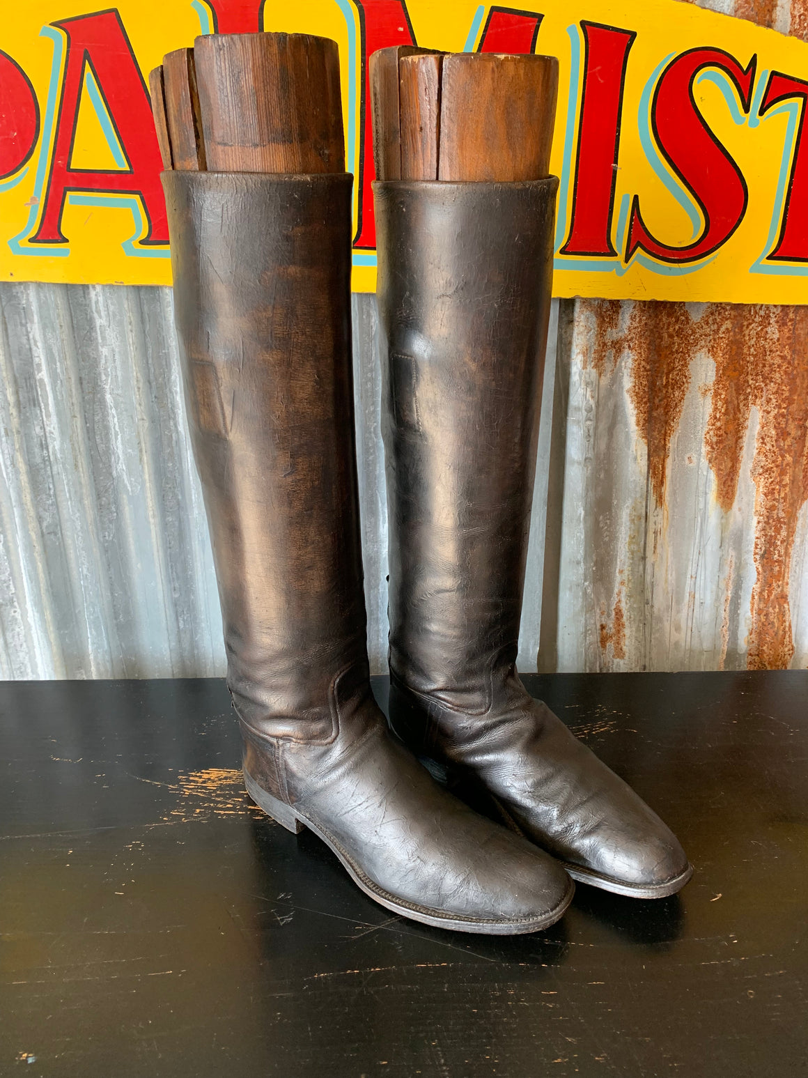 An old pair of black leather riding boots with wooden lasts