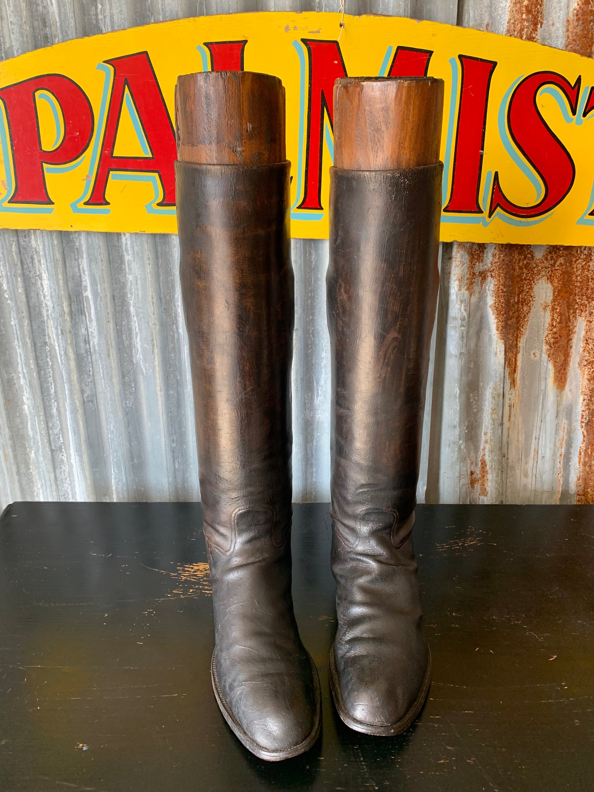 An old pair of black leather riding boots with wooden lasts