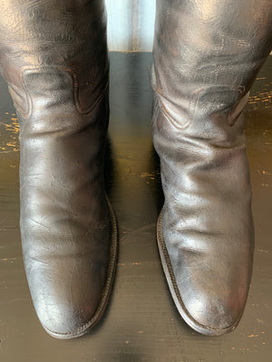An old pair of black leather riding boots with wooden lasts