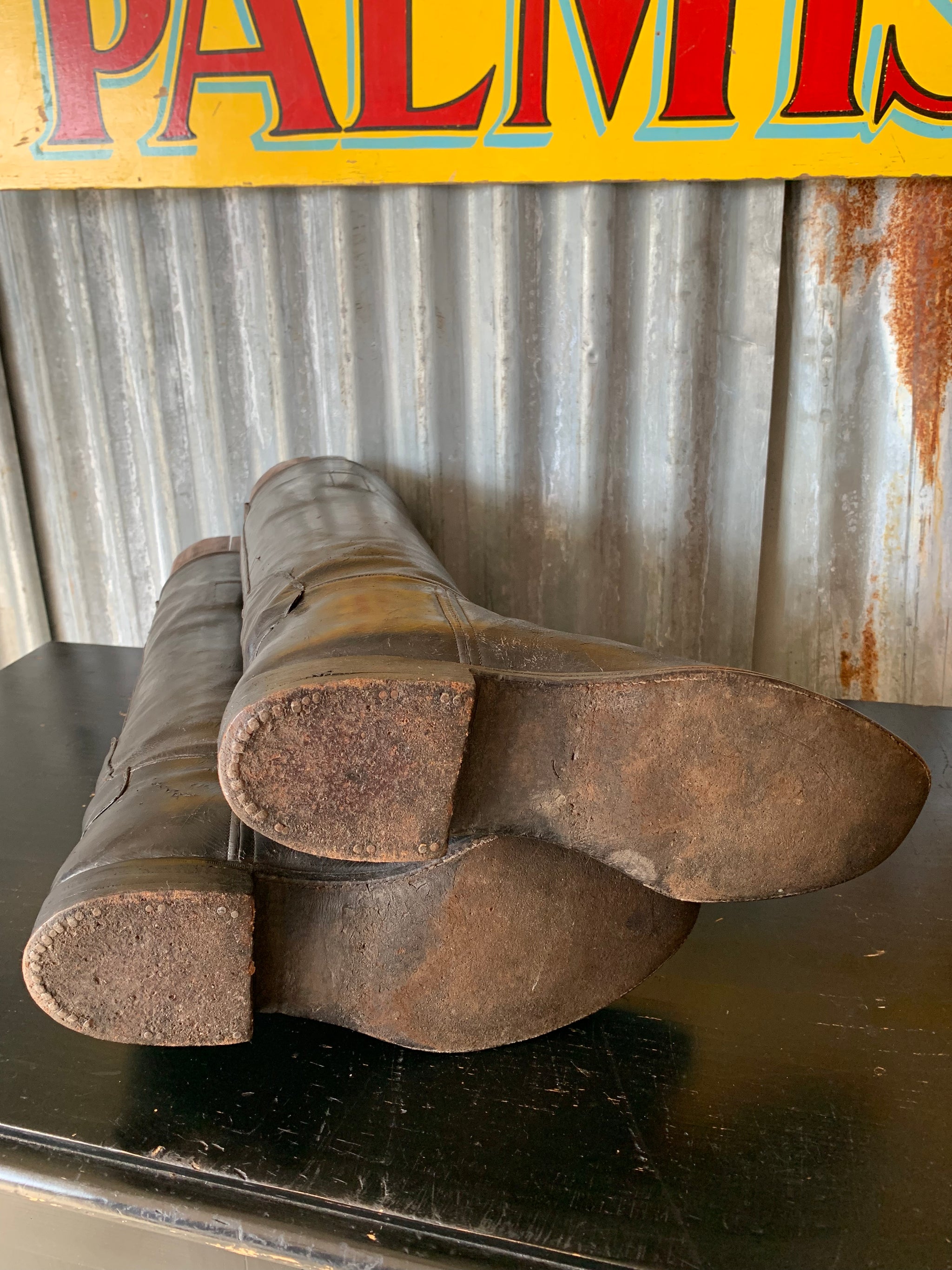 An old pair of black leather riding boots with wooden lasts
