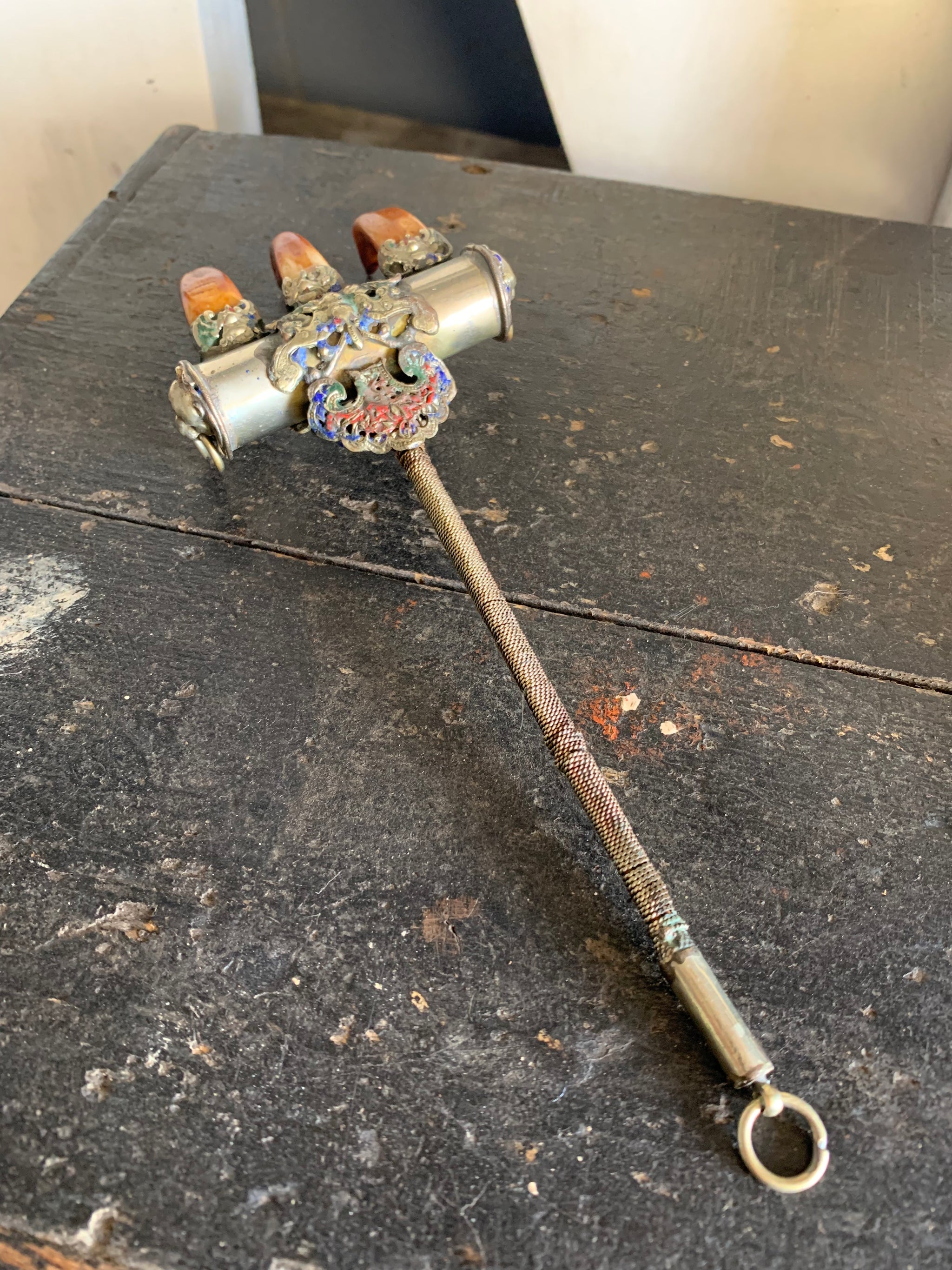 An enamelled Tibetan sliver claw back scratcher with bat and lion motifs
