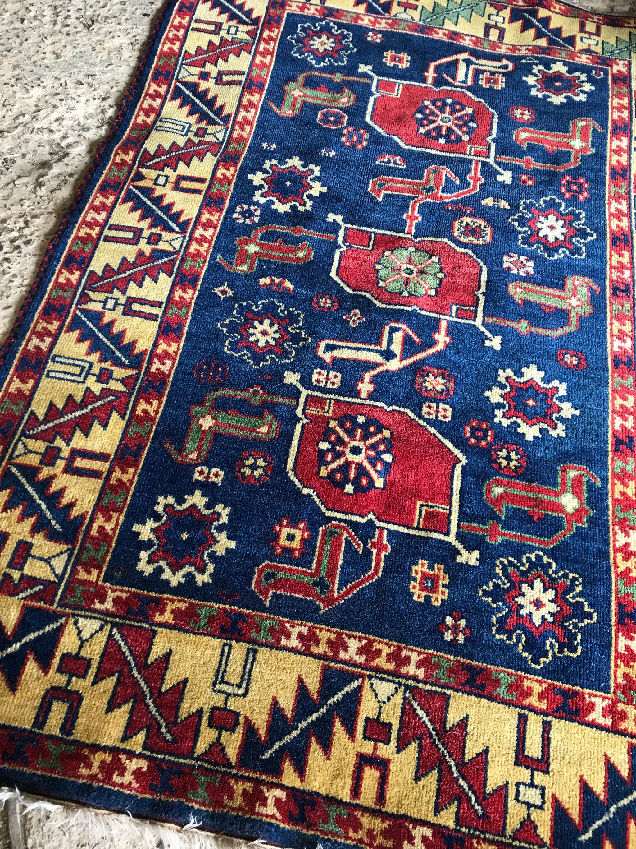 A large rectangular blue and yellow Kazak rug
