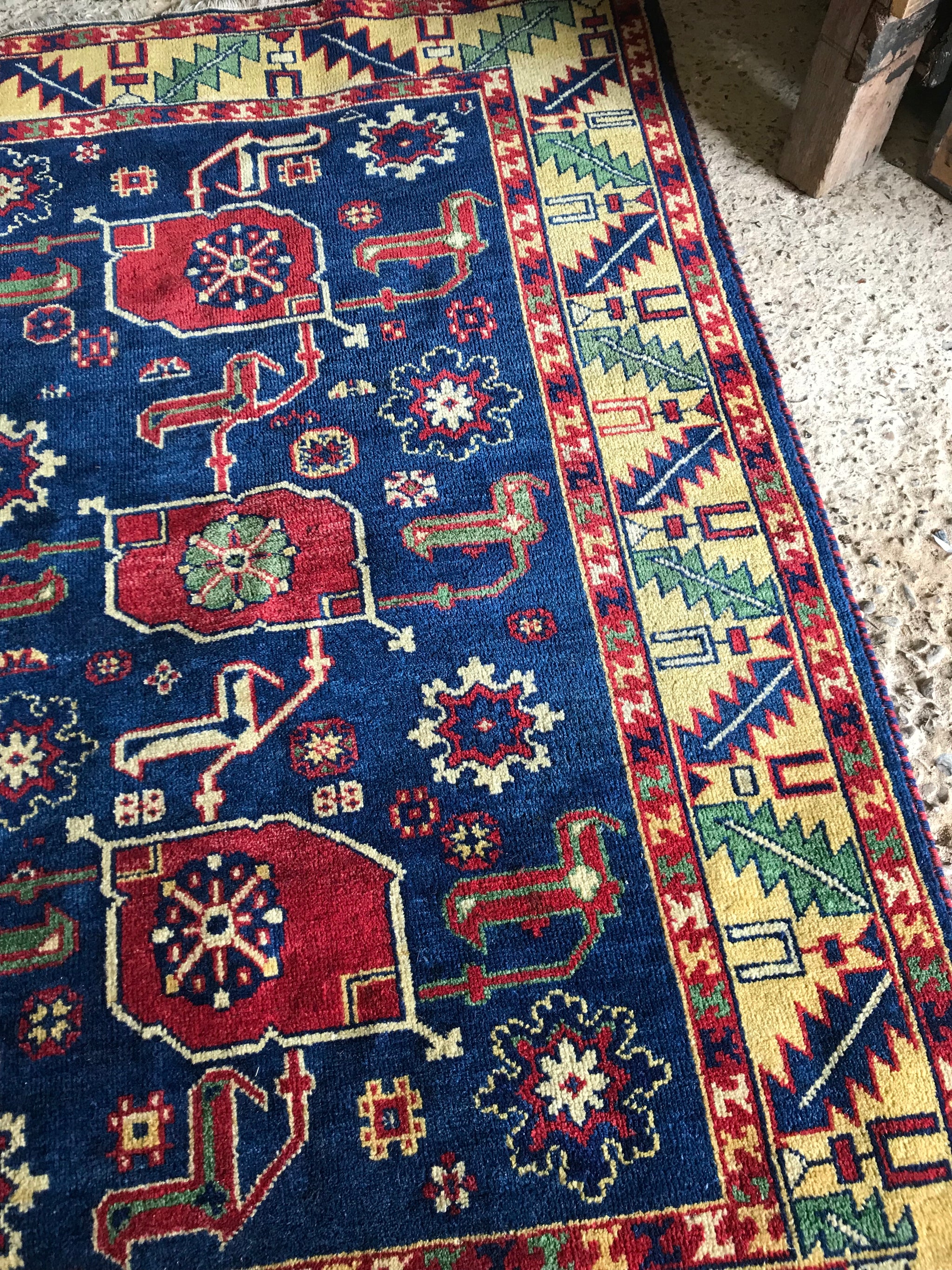 A large rectangular blue and yellow Kazak rug