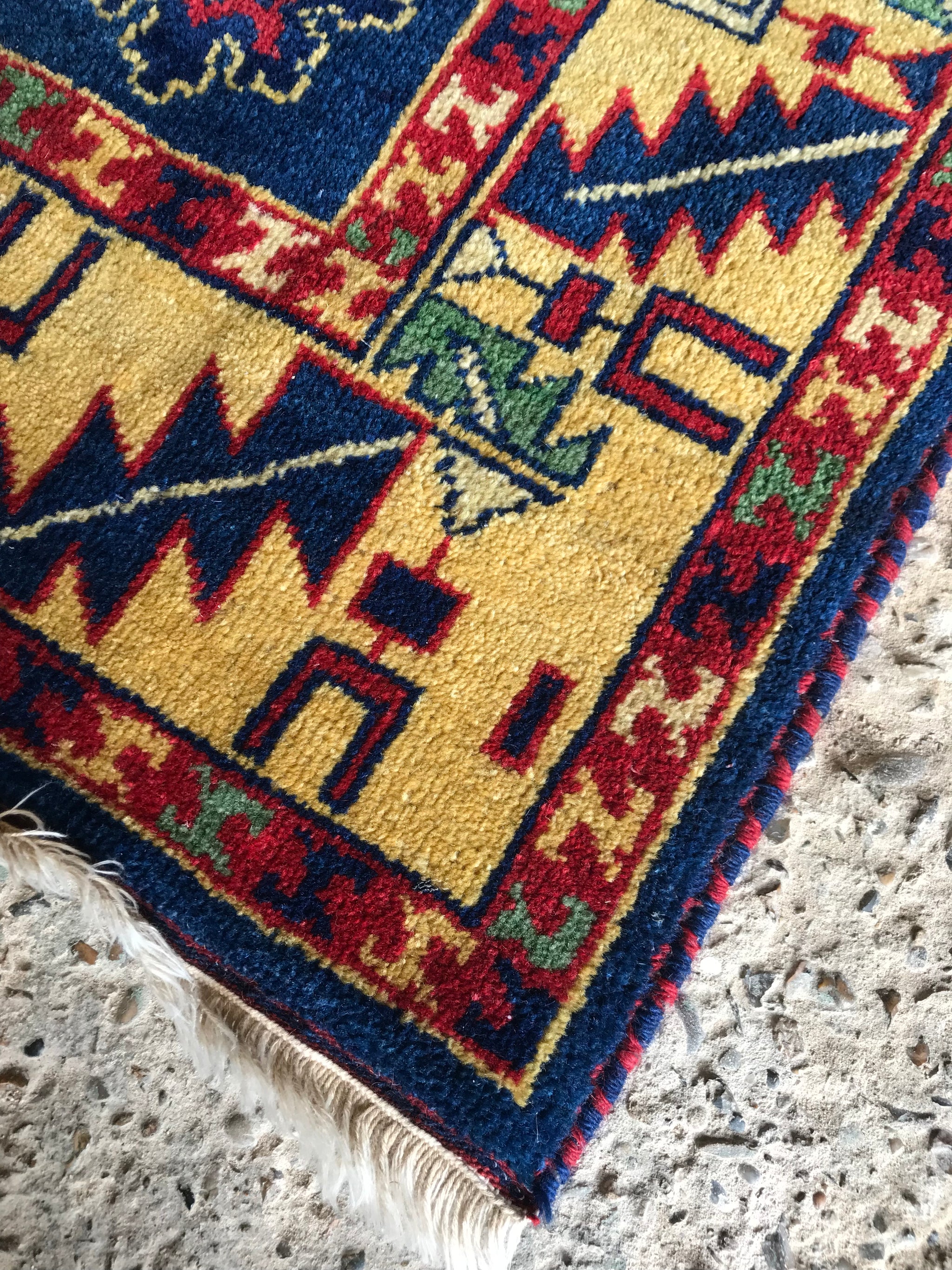 A large rectangular blue and yellow Kazak rug
