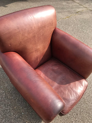 A brown leather club chair raised on castors