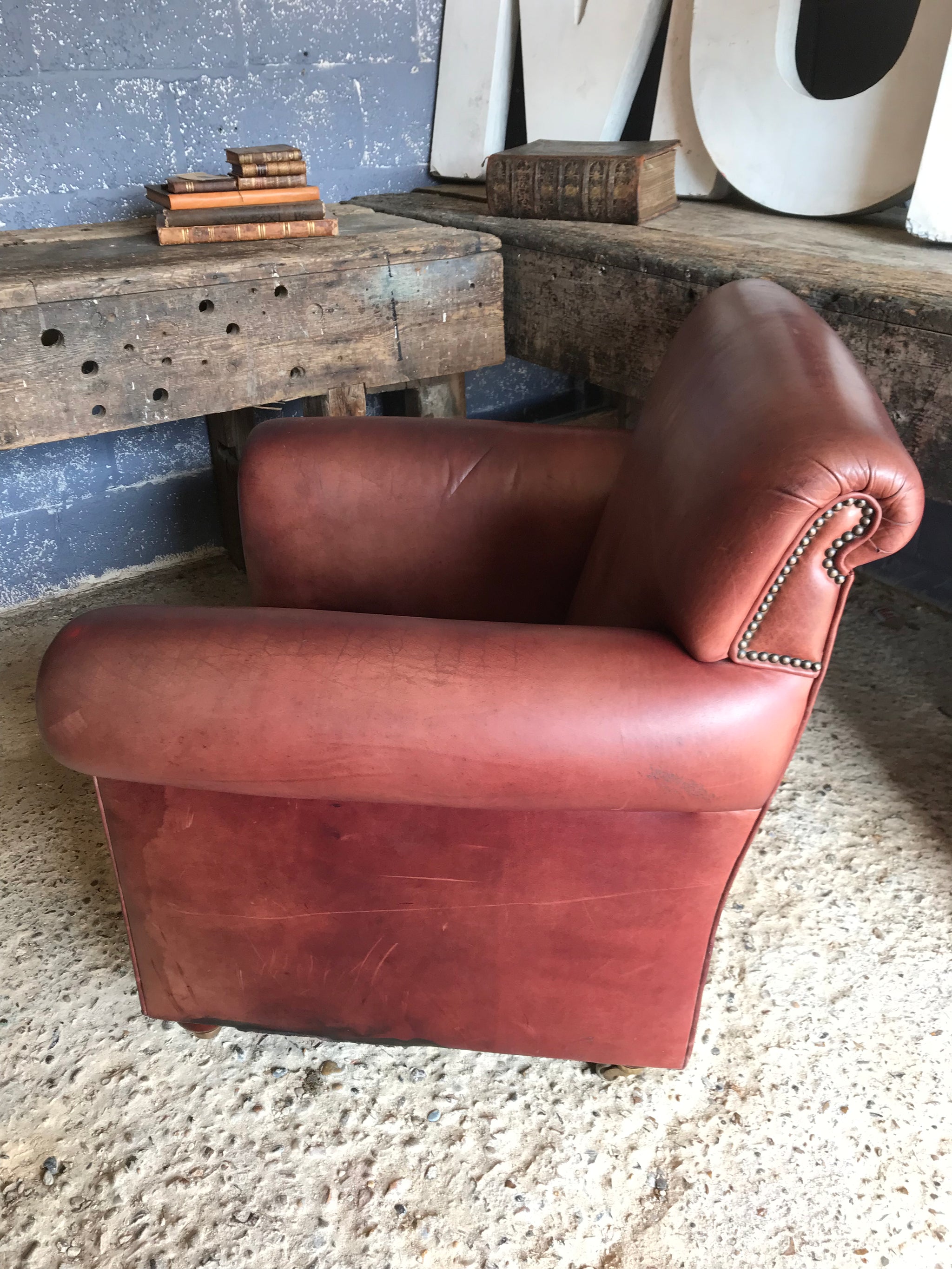 A brown leather club chair raised on castors