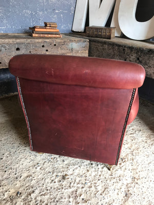 A brown leather club chair raised on castors