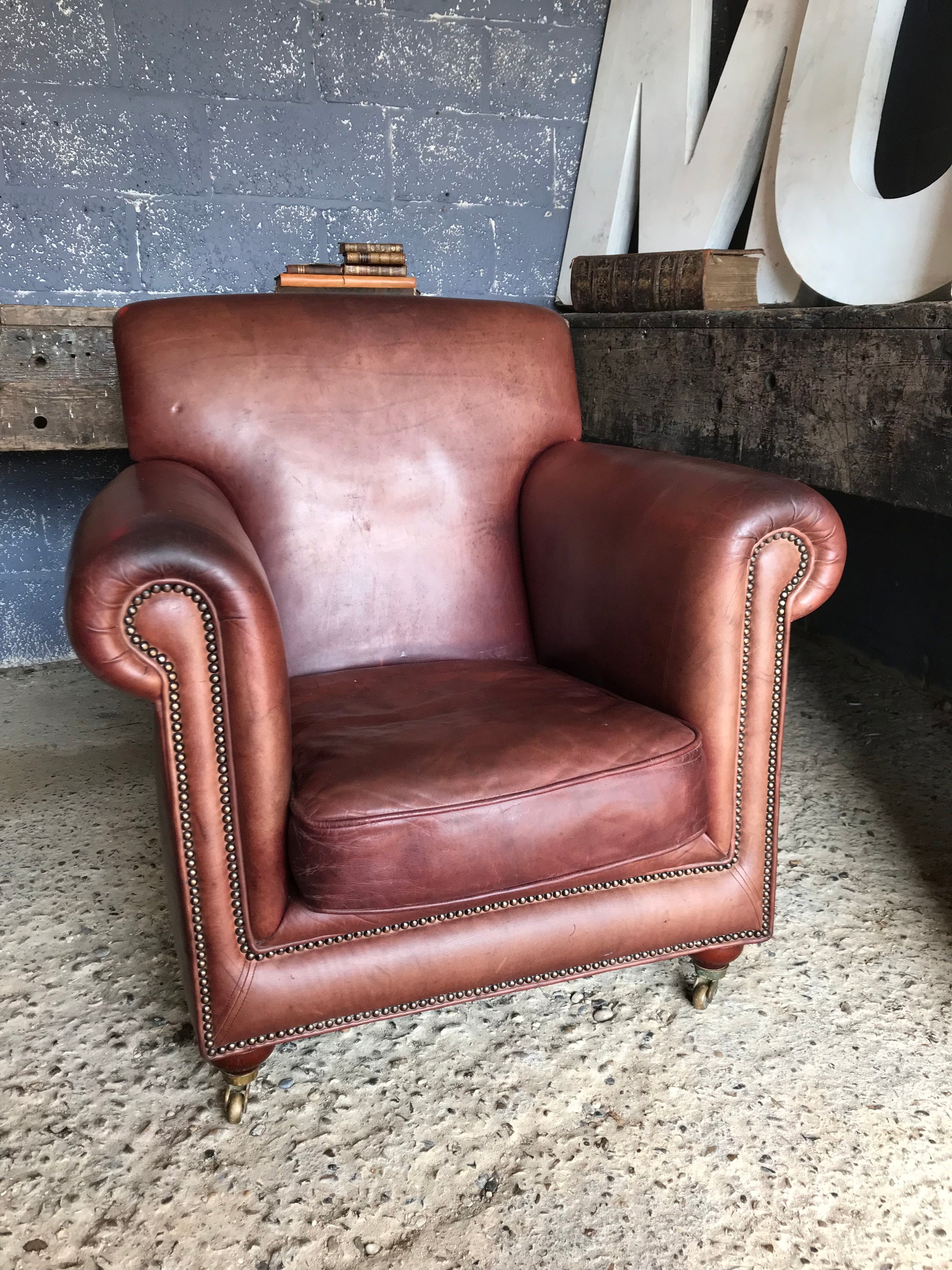 A brown leather club chair raised on castors