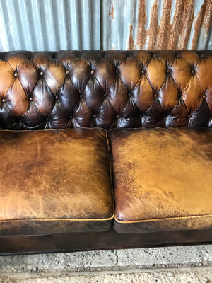 A brown leather three seater button back Chesterfield sofa