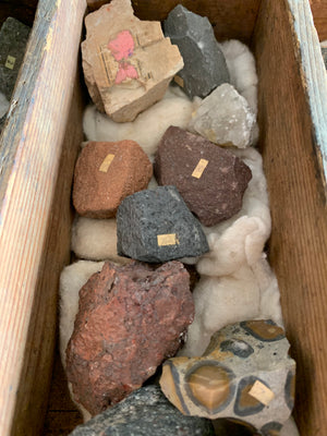 A large geological rock specimen collection in a wooden box