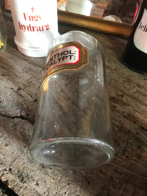 A large glass apothecary jar with hand painted gold leaf label