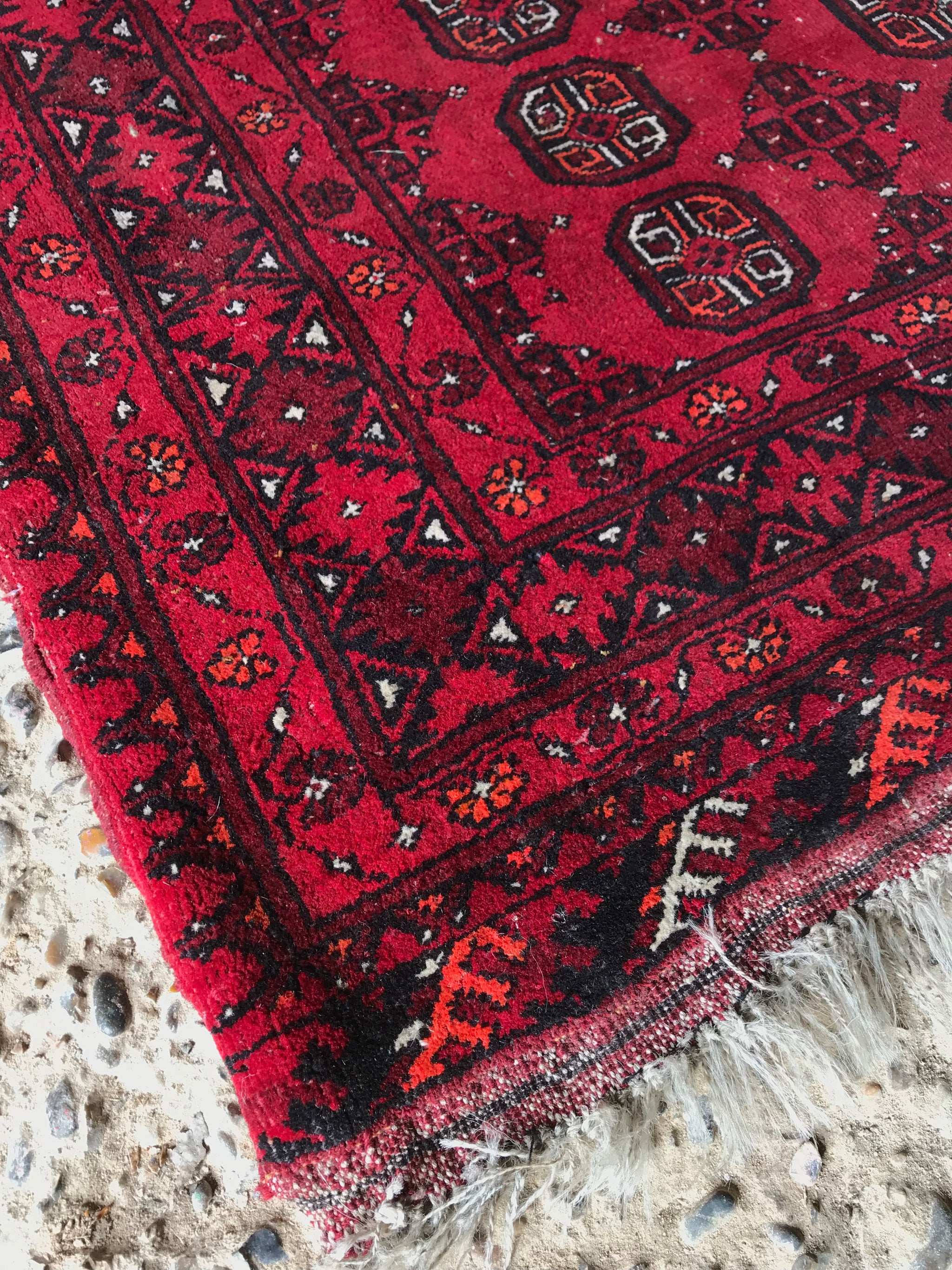 A large rectangular red Persian hand knotted wool carpet 157cm X 107cm