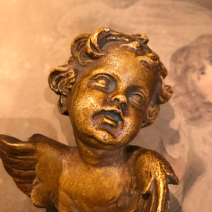 A pair of ceramic wall hanging winged putti busts