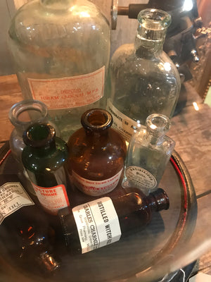 A collection of apothecary bottles and jars under a glass dome