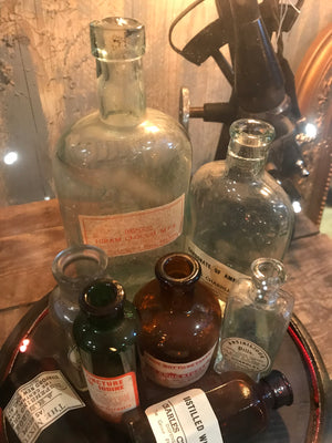 A collection of apothecary bottles and jars under a glass dome