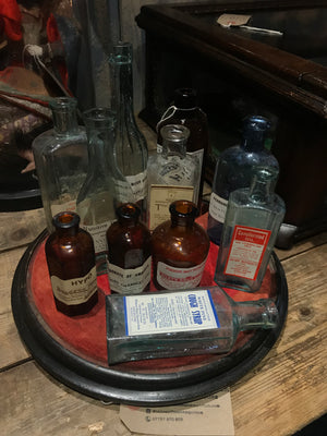 A collection of apothecary bottles and jars on a velvet base