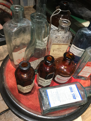 A collection of apothecary bottles and jars on a velvet base