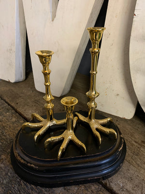 A trio of graduated gold claw candlesticks