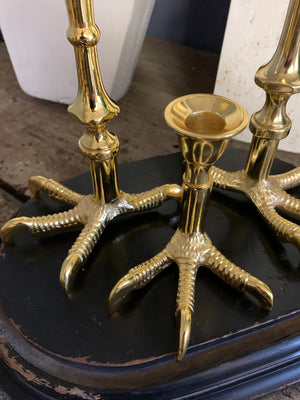 A trio of graduated gold claw candlesticks