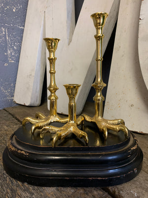 A trio of graduated gold claw candlesticks