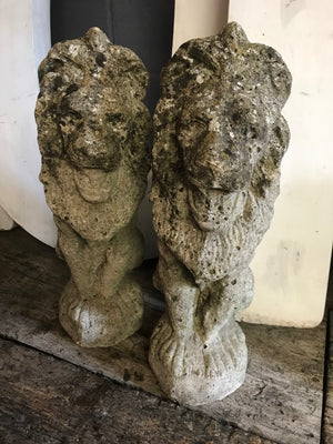 A pair of weathered cast stone lion statues