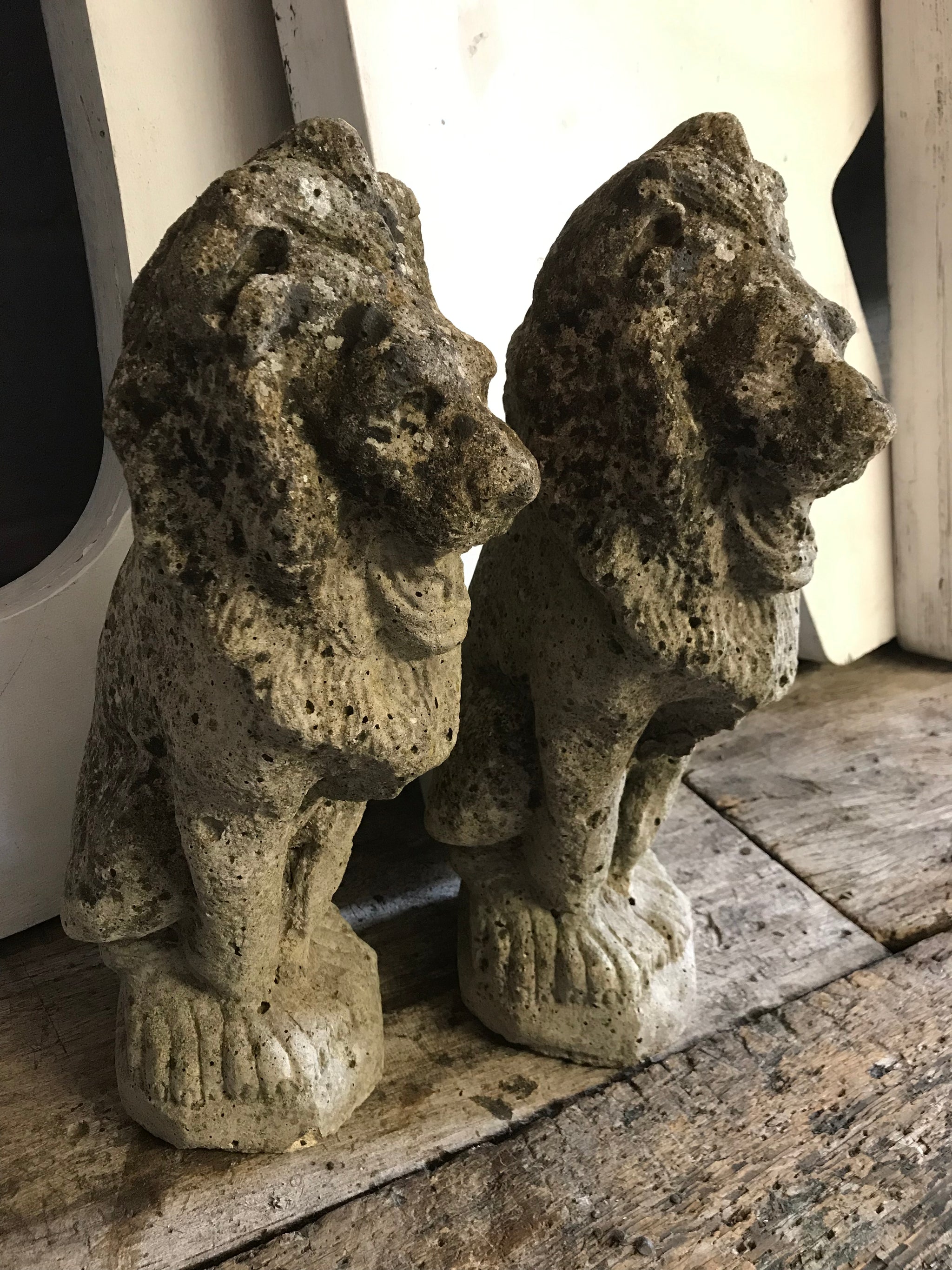 A pair of weathered cast stone lion statues