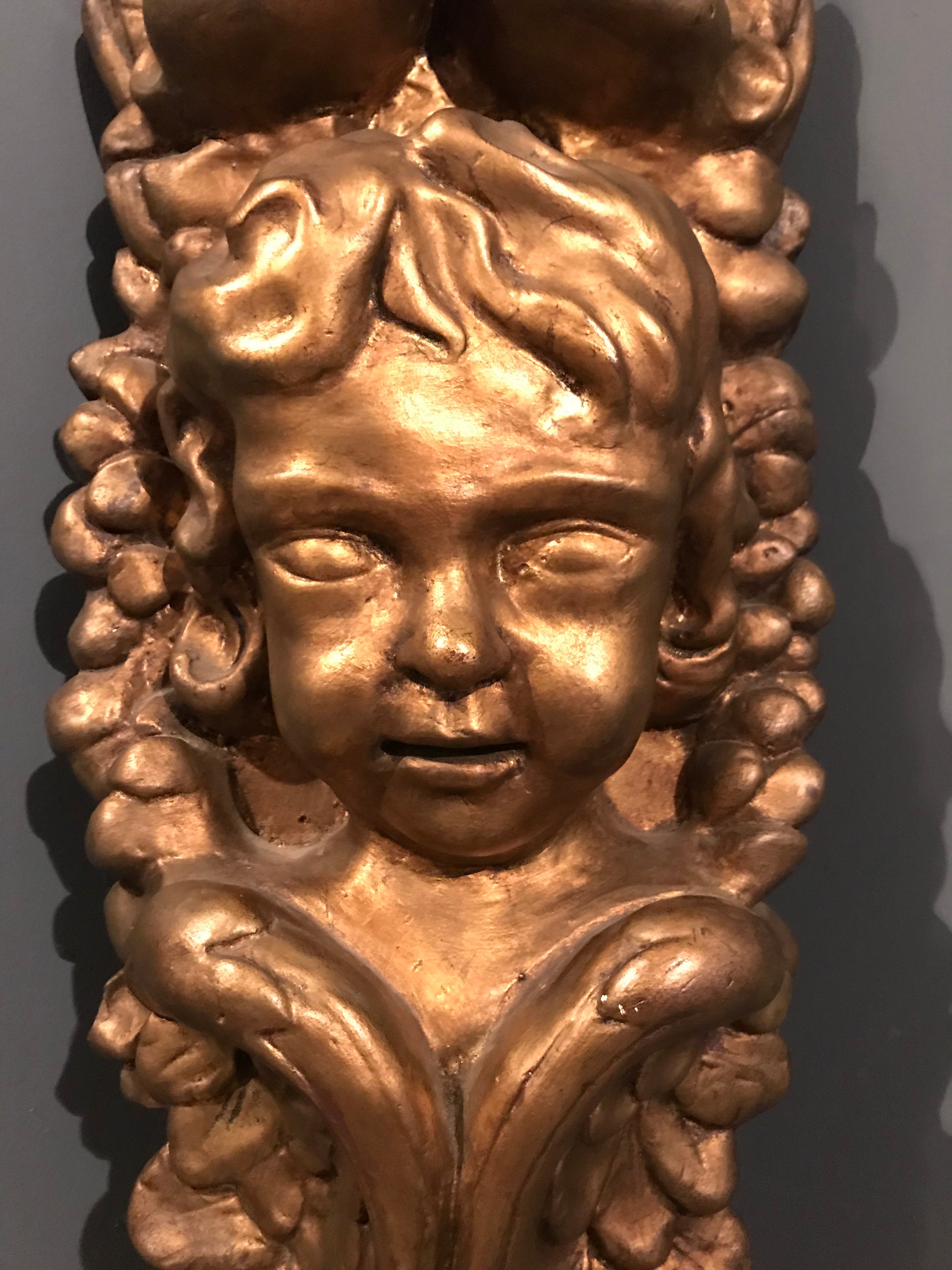 A gilt classical putto plaster wall plaque