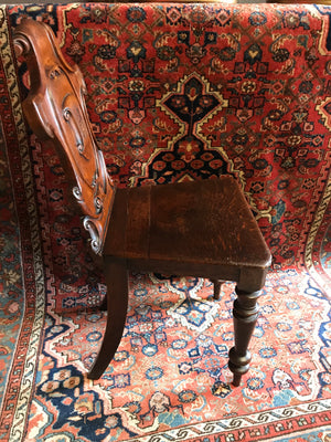 A 19th Century carved wood hall chair with monogrammed armorial crest