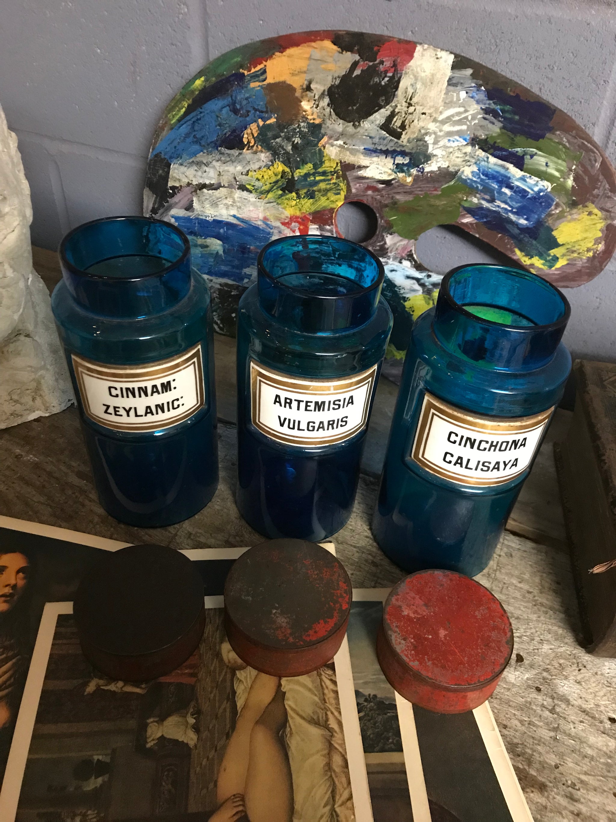 A set of three blue glass apothecary jars with toleware lids
