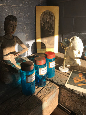 A set of three blue glass apothecary jars with toleware lids