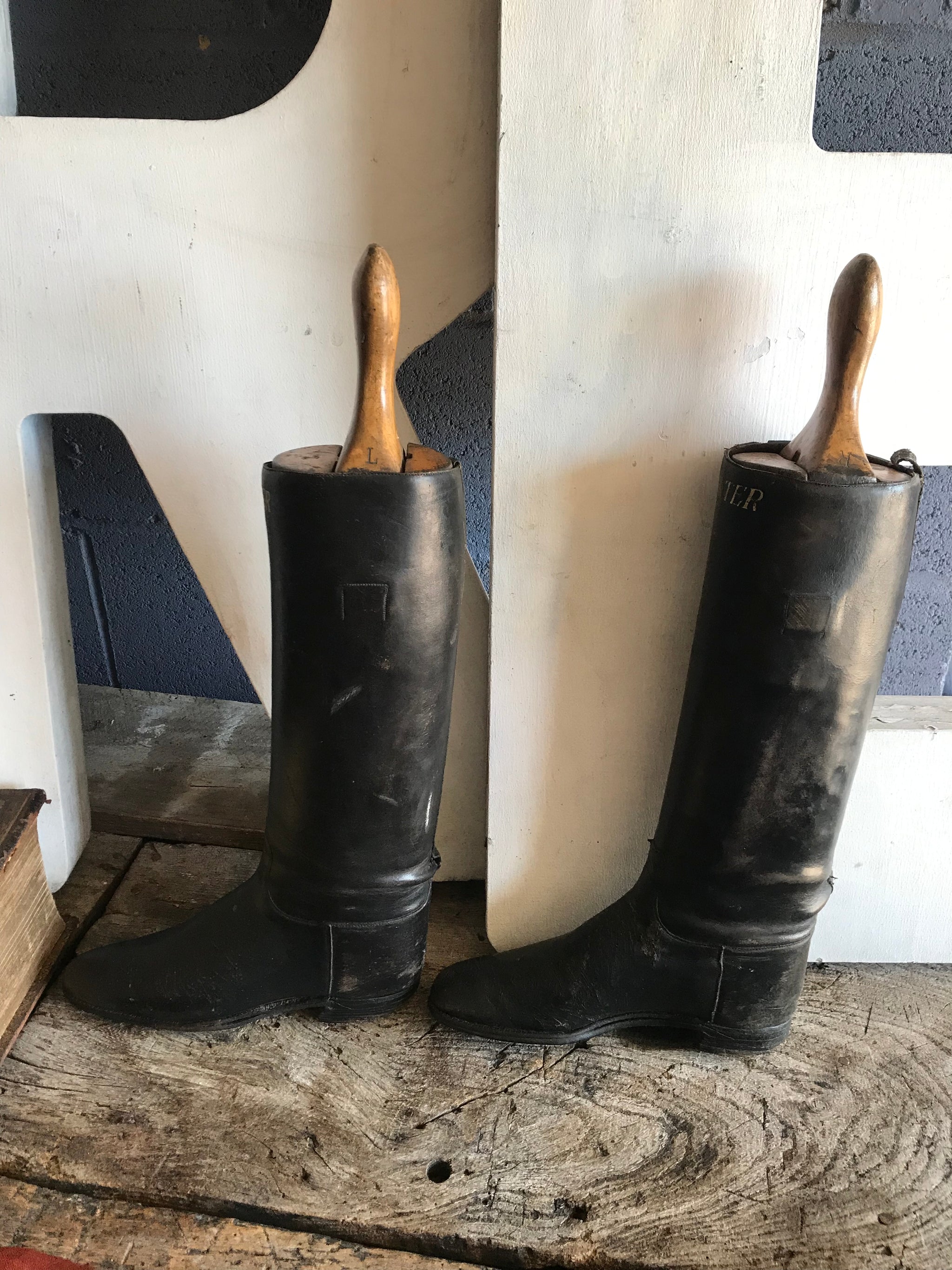 A pair of black leather riding boots with wooden lasts