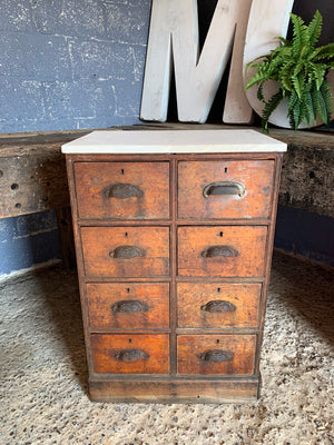 A wooden apothecary bank of drawers with Portland stone top