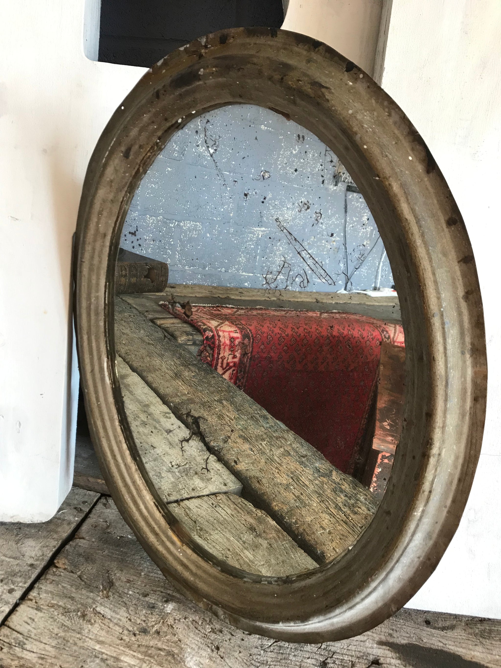 A distressed oval gilt wall mirror