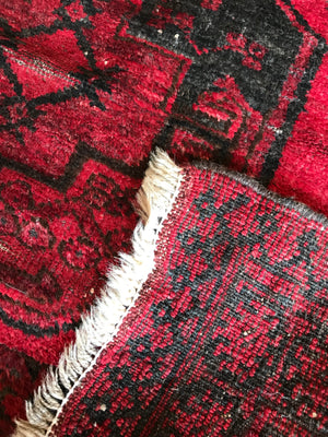 A Persian red ground lozenge rectangular rug
