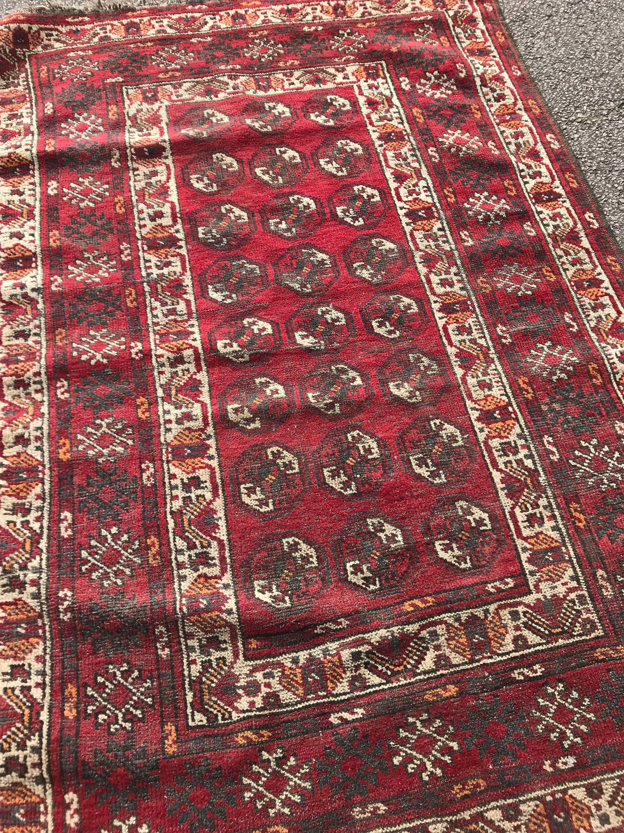 A Persian red ground lozenge rectangular rug