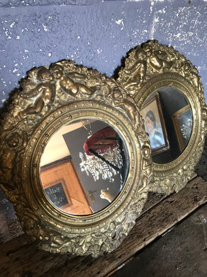 A pair of 19th Century brass repoussé mirrors with cherub detailing