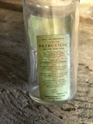 A small glass Orthoxicol Syrup apothecary bottle