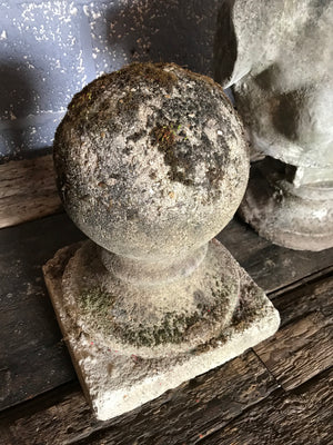 A pair of mossy stone ball pillar caps