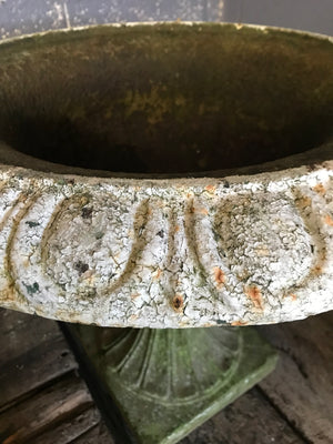 A 19th century white cast iron garden urn on a stone base