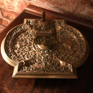 A rococo brass cherub and lion head inkwell and pen tray