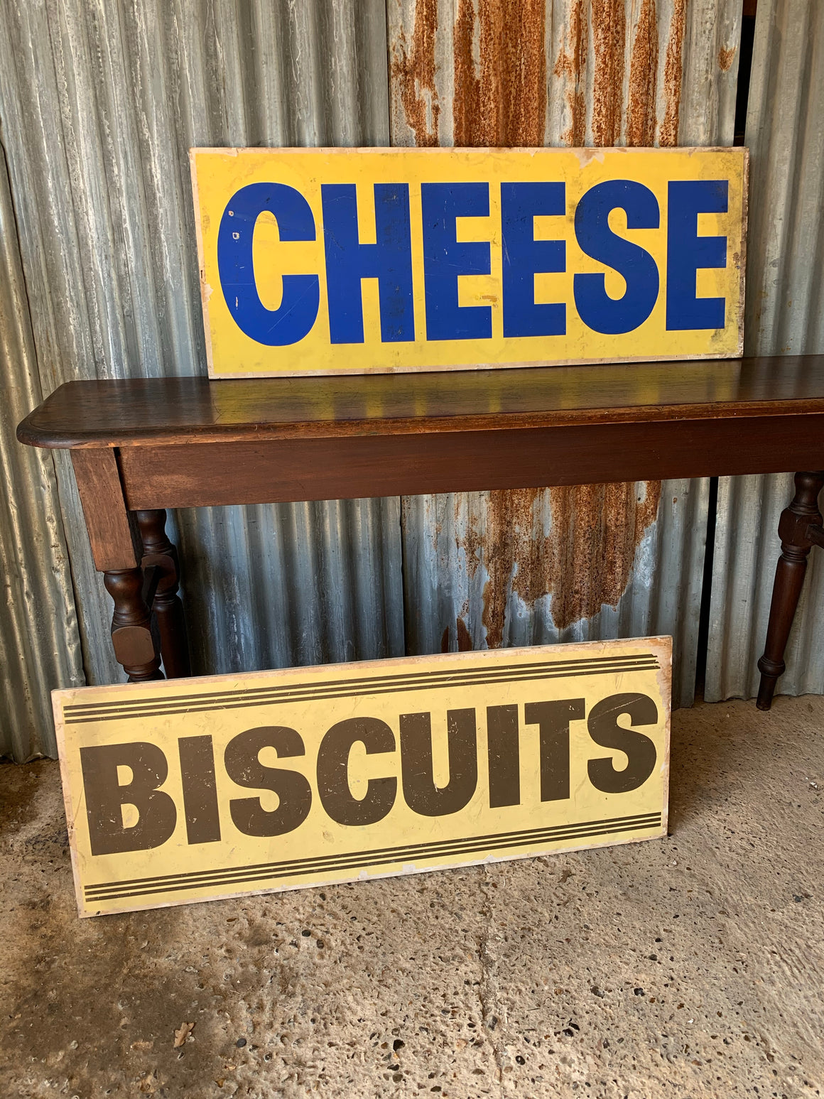 A pair of grocery shop advertising trade signs: cheese & biscuits