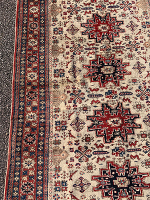 A cream ground Persian rectangular rug with long fringe- 260cm x 134cm