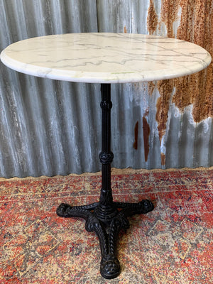 A black cast iron bistro table with marble top