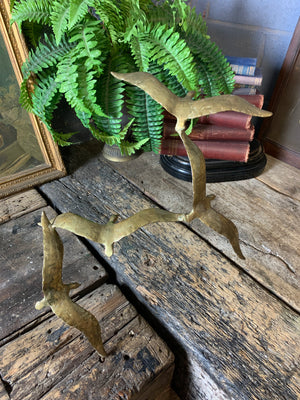 A trio of gilded bronze flocks of birds in flight