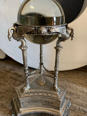 A large fortune teller's crystal ball on a silver plate swan stand