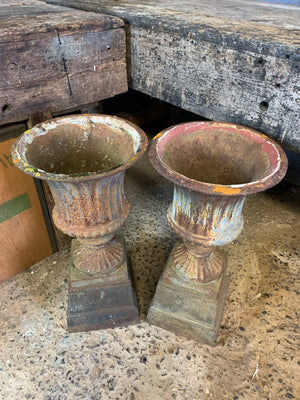 A large pair of cast iron campana urns on pedestals